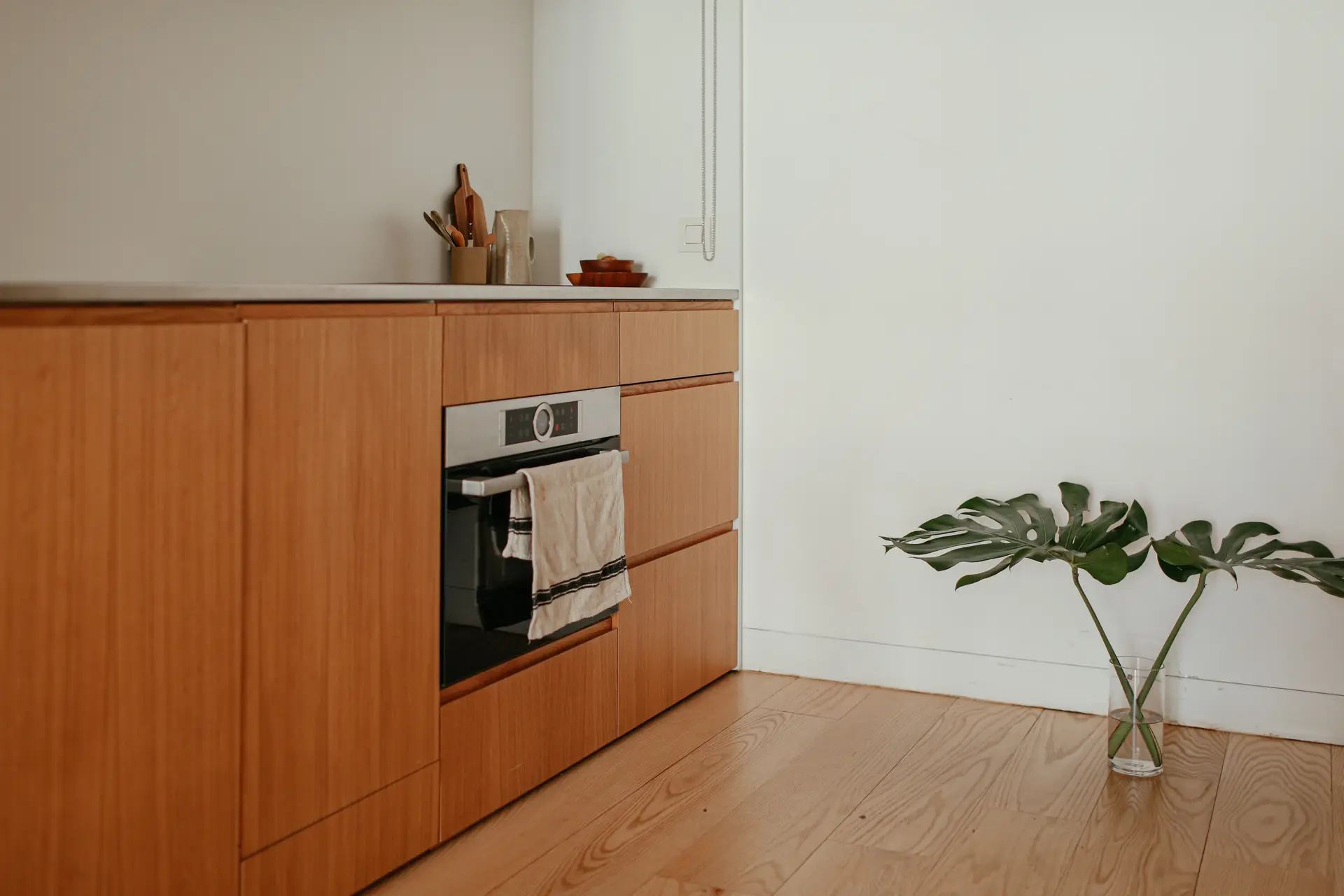 Moderni minimalistinen keittiö puukaapistoilla ja integroidulla tasovalolla